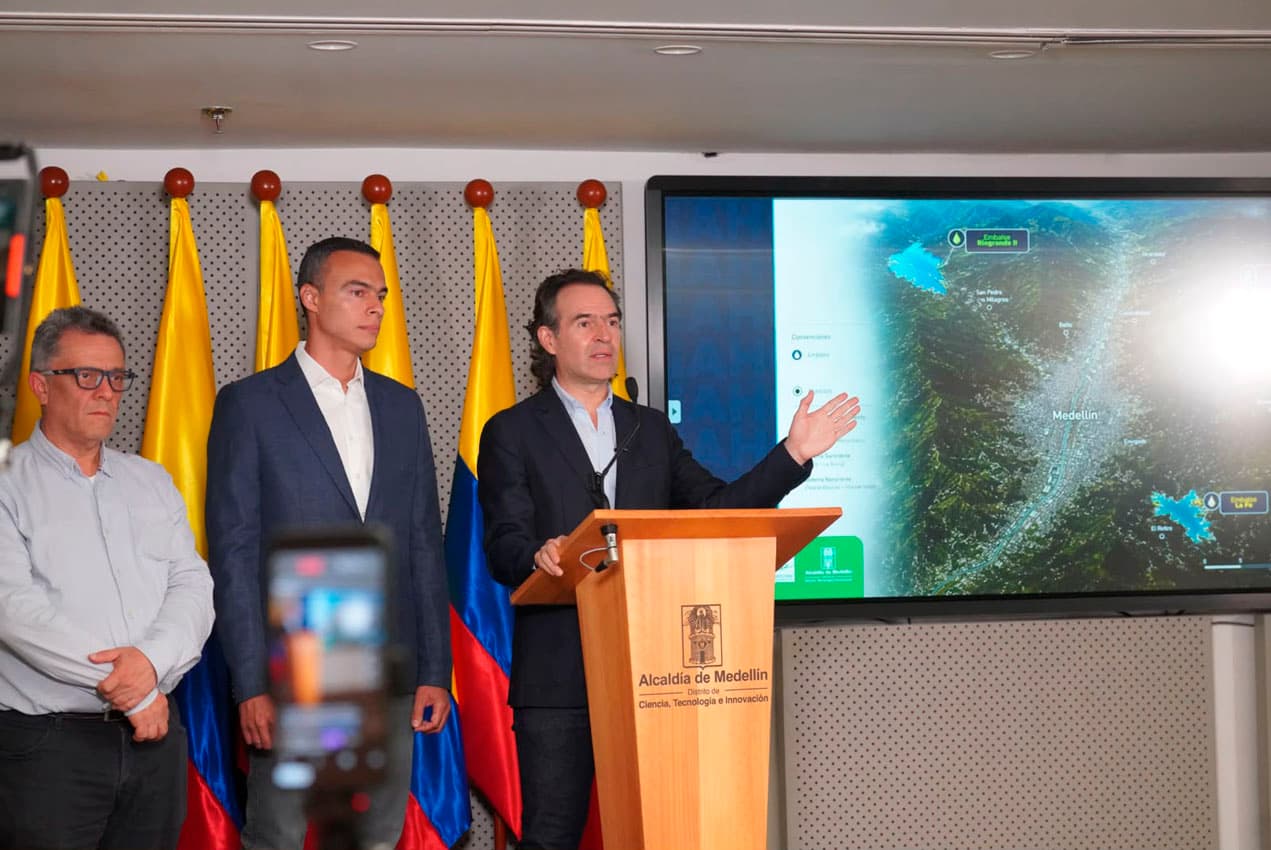 Federico Gutiérrez anuncia la pausa del racionamiento en una rueda de prensa en Medellín el 14 de septiembre, ante un mapa de los embalses y acompañado de funcionarios.