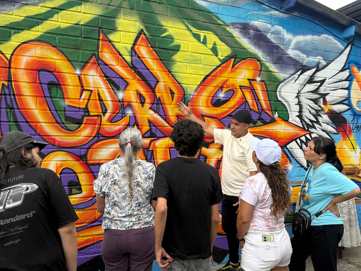 Personas adultas frente a un mural colorido en imagen difundida por la Alcaldía de Bello con su boletín de estímulos culturales. Foto de contexto · fecha de toma no verificada.