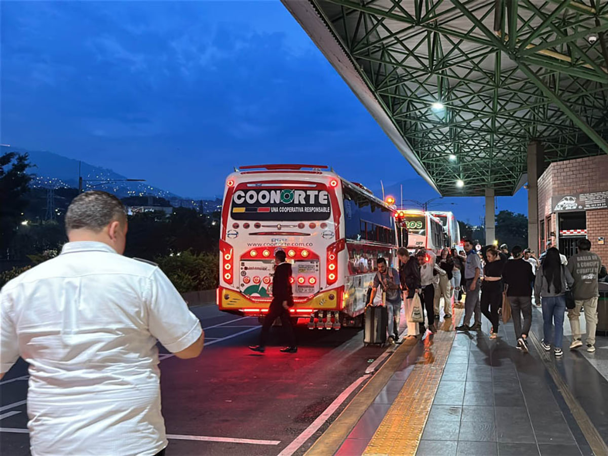 Bus Coonorte y viajeros con maletas en un andén de la imagen oficial de Terminales Medellín. Foto de contexto · fecha de toma no verificada.